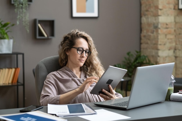 Schwangere Geschäftsfrau, die an Tablet-PC arbeitet