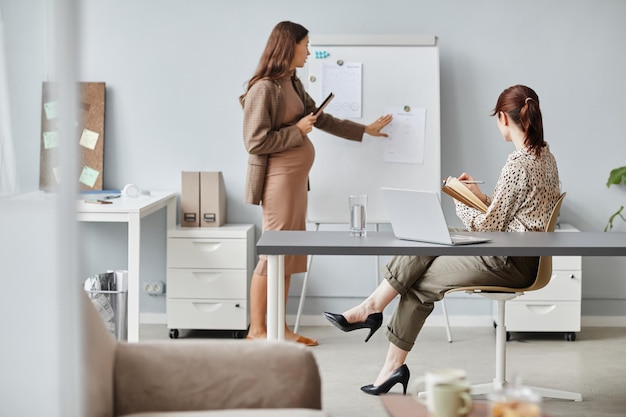 Schwangere Geschäftsfrau, die bei der Konferenz arbeitet