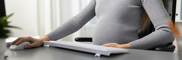 Foto schwangere geschäftsfrau, die im büro mit computer arbeitet