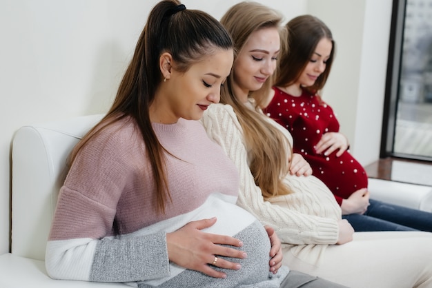 Schwangere halten ihren Bauch mit den Händen in Nahaufnahme. Vorgeburtliche Klasse schwangerer Frauen