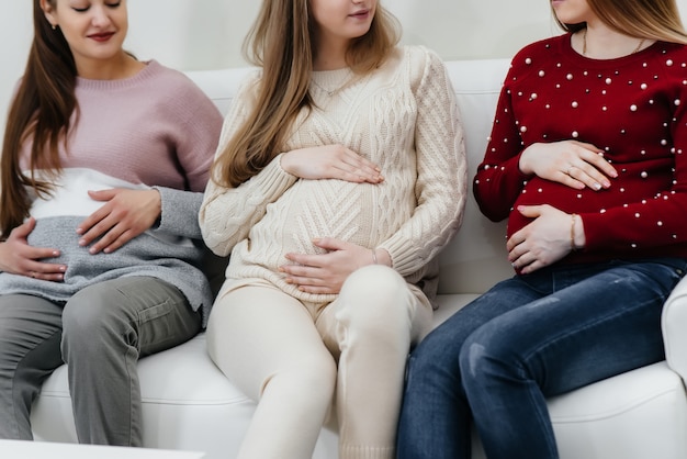 Schwangere halten ihren Bauch mit den Händen in Nahaufnahme. Vorgeburtliche Klasse schwangerer Frauen
