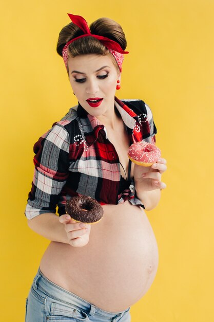 Schwangere im Pin-up-Stil mit zwei Donuts in der Hand