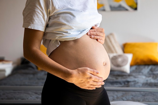 Schwangere junge Frau hört dem Baby zu, das ihren Bauch drückt