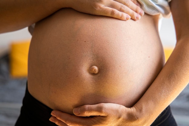 Schwangere junge Frau hört dem Baby zu, das ihren Bauch hält