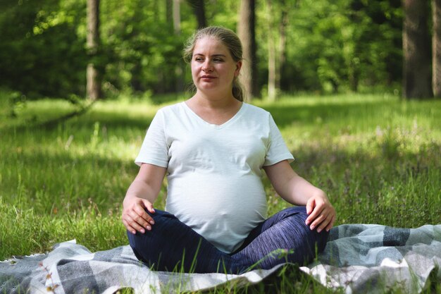 Foto schwangere junge frau sitzt in der natur und meditiert oder entspannt sich frieden und ruhe konzept der schwangerschaft und mutterschaft