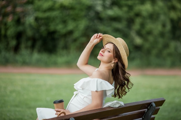 Schwangere junge schöne Frau trinkt Cappuccino im Park