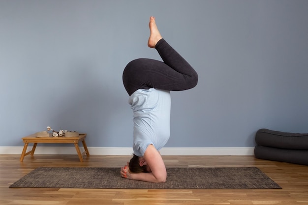 Schwangere kaukasische Frau, die Übungen macht, während sie in einer Yoga-Pose auf dem Kopf steht