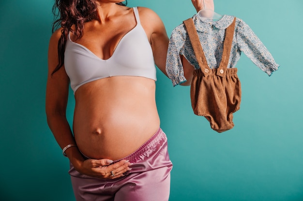 Schwangere Mama bereitet die Kleidung für das Baby vor
