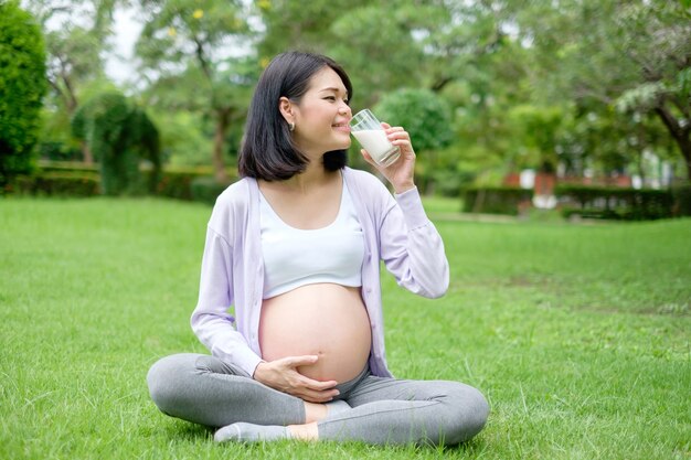 Schwangere Mutter sitzt und trinkt Milch für eine gute Gesundheit im Park