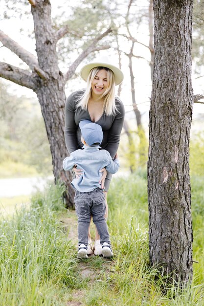 Schwangere Mutter und ihr kleiner Sohn gehen im Wald spazieren und verbringen Zeit miteinander