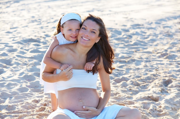 Schwangere Mutter und Tochter am Strand