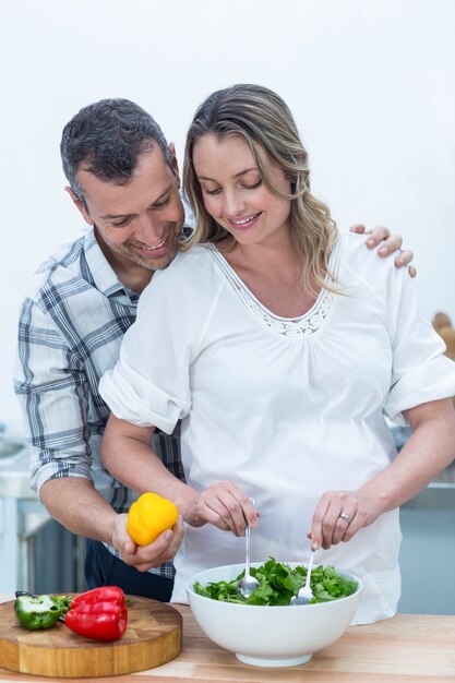 Schwangere Paare, die Salat in der Küche zubereiten