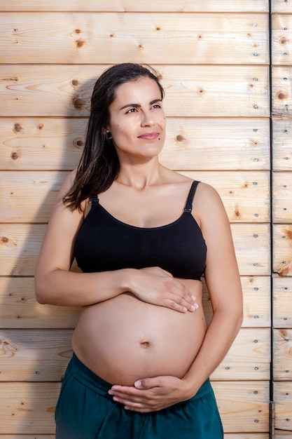 Schwangere posiert mit den Händen auf dem Bauch