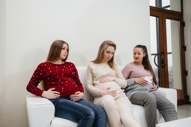 Schwangere sitzen auf der Couch und haben Spaß miteinander zu plaudern