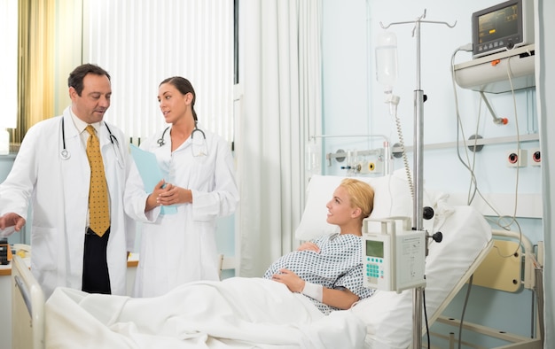 Schwangerer Patient in ihrem Bett, das mit Doktoren spricht