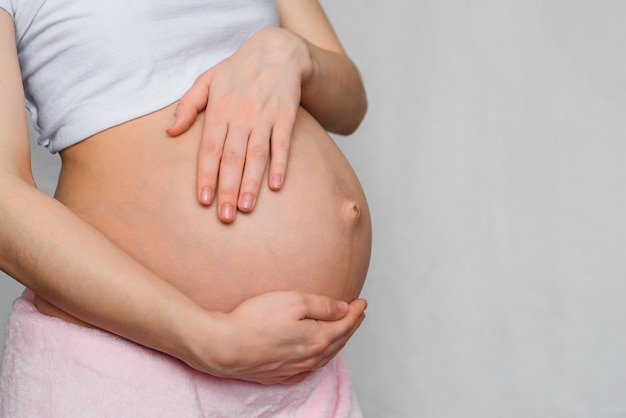 Schwangeres Mädchen, das ihren Bauch mit ihren Händen umarmt