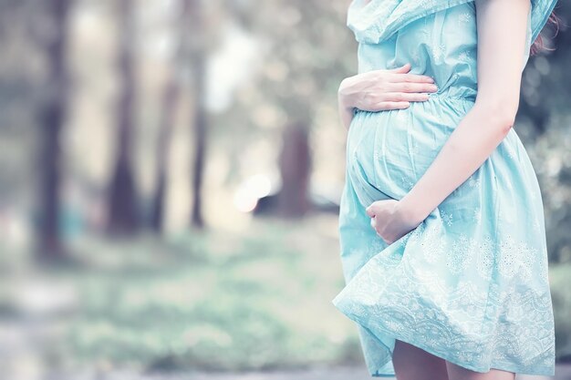 Schwangeres Mädchen in einem Kleid in der Natur auf einem SpaziergangxA