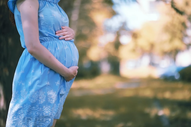 Schwangeres Mädchen in einem Kleid in der Natur bei einem Spaziergang