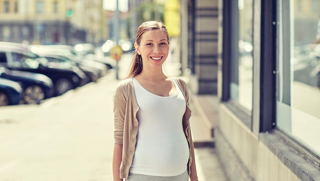 schwangerschaft, mutterschaft, menschen und erwartungskonzept - glücklich lächelnde schwangere frau auf der stadtstraße