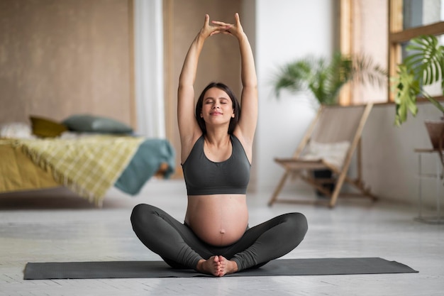 Foto schwangerschaft yoga ruhig schöne schwangere frau stretching auf fitness-matte zu hause