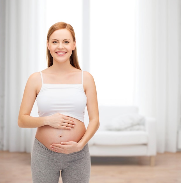 schwangerschafts-, mutterschafts- und glückskonzept - glückliche zukünftige mutter, die ihren bauch berührt