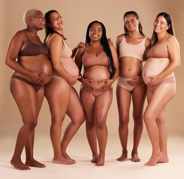 Foto schwangerschaftsgemeinschaft und porträt von freunden im studio für diversität, mutterschaft und pränatales wohlbefinden. mutterschaftsliebe und schwangere frauen zeigen gemeinsam ihren babybauch vor beigem hintergrund