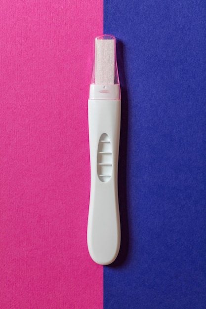 Schwangerschaftstest auf blauem und rosafarbenem Hintergrund