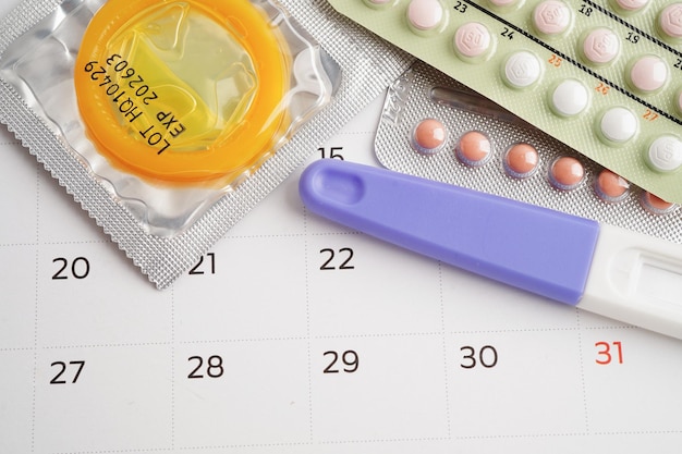 Schwangerschaftstest mit Geburtenkontrollepillen und Kondom für Frauen am Kalendertag des Eisprungs