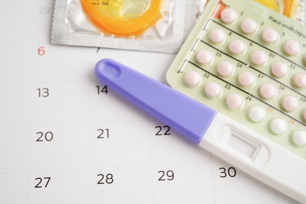 Schwangerschaftstest mit Geburtenkontrollepillen und Kondom für Frauen am Kalendertag des Eisprungs