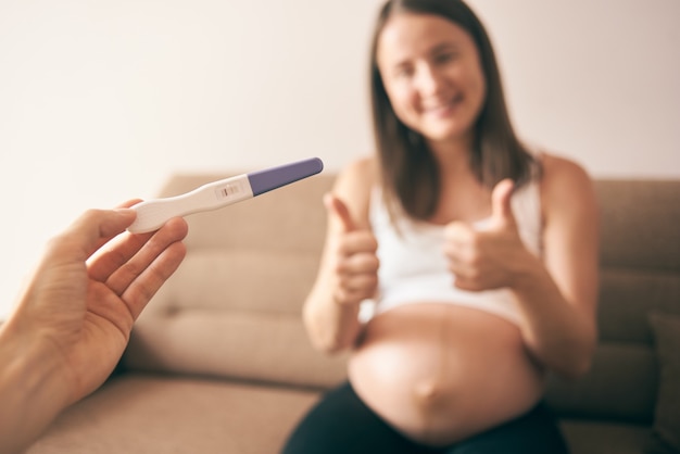 Schwangerschaftstest und glückliche schwangere Frau im Hintergrund