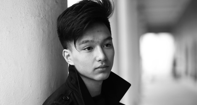 Schwarz-Weiß-Foto eines asiatischen jungen Mannes, der draußen vor der Kamera posiert