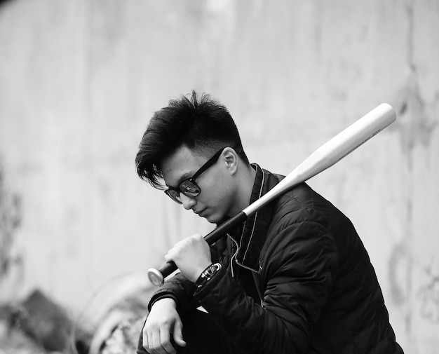 Schwarz-Weiß-Foto eines asiatischen jungen Mannes, der draußen vor der Kamera posiert