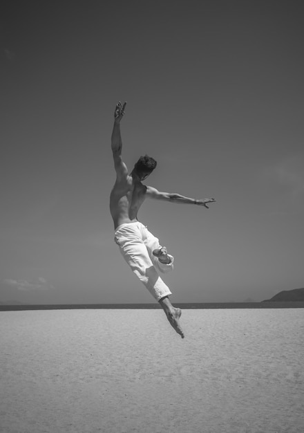 Schwarz-Weiß-Foto eines Mannes, der am Strand tanzt Mann, der zeitgenössischen Tanz tanzt