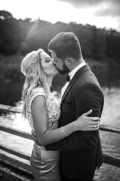 Foto schwarz-weiß-foto, stilvolles brautpaar, das am hochzeitstag auf einer brücke posiert