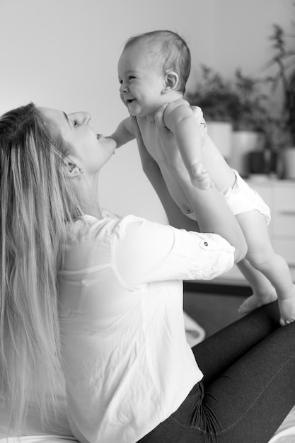 Schwarz-Weiß-Porträt der glücklichen Mutter, die ihr fröhliches Baby umarmt