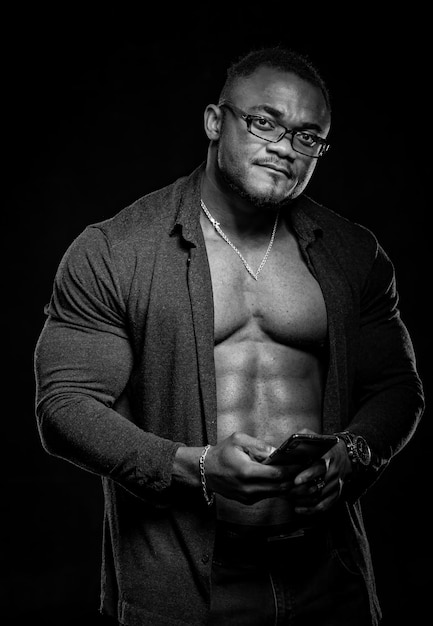 Foto schwarz-weiß-porträt des afroamerikanischen bodybuilders mit hemdlosem, muskulösem oberkörper. männliche tragende jeans lokalisiert auf schwarzem hintergrund