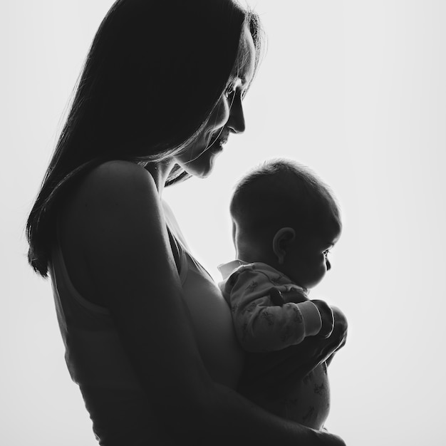 Foto schwarz-weiß-porträt im profil einer jungen frau und eines neugeborenen, drückte die frau das baby an seine brust