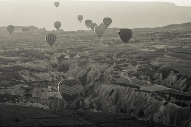Schwarz-weißer Heißluftballon, der über die Felslandschaft in Kappadokien, Türkei, fliegt