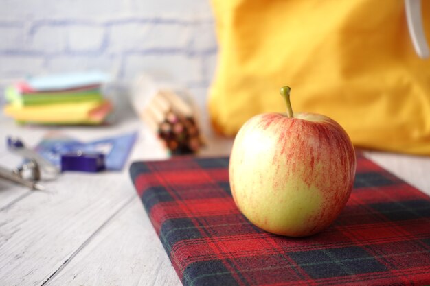 Schwarz zum Schulkonzept mit Apfel auf Notizblock auf Tisch