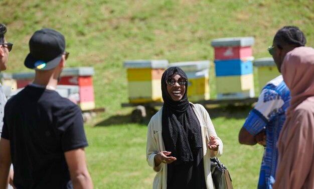 schwarzafrikanische muslimische Frau, die einer Gruppe von Geschäftsinvestoren oder Touristen auf einer kleinen lokalen Honigproduktionsfarm eine Präsentation gibt