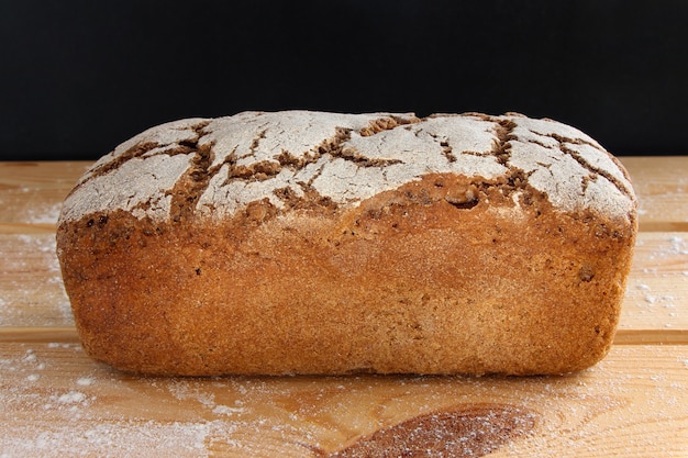 Schwarzbrot mit Mehl auf einem Holztisch