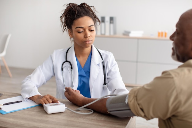 Schwarze Ärztin, die den Druck auf der Hand des Patienten misst