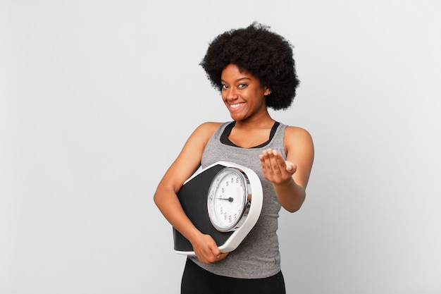 Schwarze Afro-Fitness-Frau mit Waage oder Waage