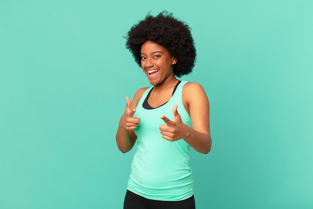 Schwarze Afro-Frau, die sich glücklich, cool, zufrieden, entspannt und erfolgreich fühlt, wenn sie nach vorne zeigt