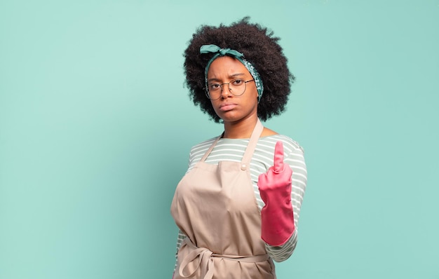 Schwarze Afro-Frau, die sich wütend, verärgert, rebellisch und aggressiv fühlt, den Mittelfinger dreht und sich wehrt. Hauswirtschaftskonzept .. Haushaltskonzept