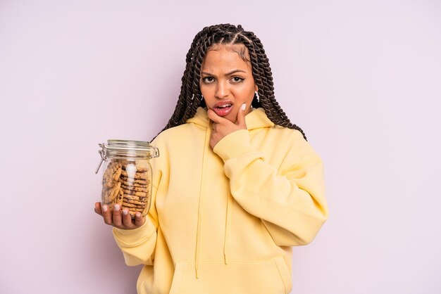 Schwarze Afro-Frau mit weit geöffnetem Mund und Augen und Hand am Kinn. Cookies-Konzept