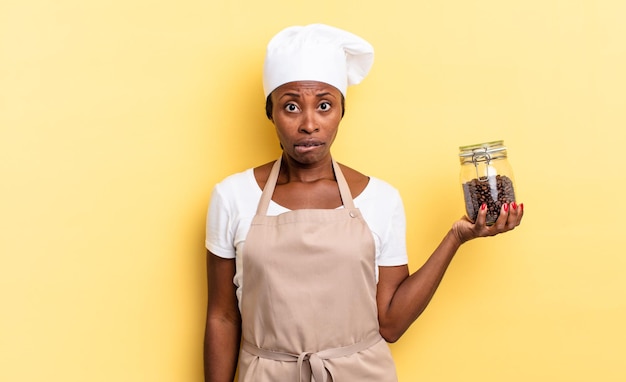 Schwarze Afro-Köchin, die verwirrt und verwirrt aussieht und mit einer nervösen Geste auf die Lippen beißt, ohne die Antwort auf das Problem der Kaffeebohnen zu kennen