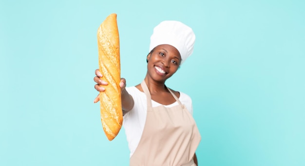 Schwarze afroamerikanische erwachsene Kochfrau, die ein Brotstangenbrot hält