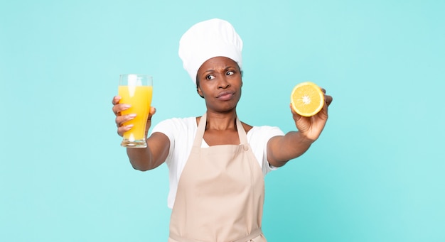 Schwarze afroamerikanische erwachsene Kochfrau. Orangensaft Konzept