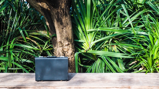 Schwarze Business-Leder-Aktentasche, Handtasche mit Schlüsselschloss im Büro, auf Holzoberfläche mit grünem Naturhintergrund